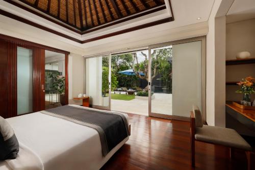 a bedroom with a bed and a sliding glass door at Villa Camellia by Nakula in Jimbaran
