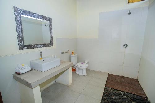 a white bathroom with a sink and a toilet at D'Muncuk Huts Lembongan in Nusa Lembongan