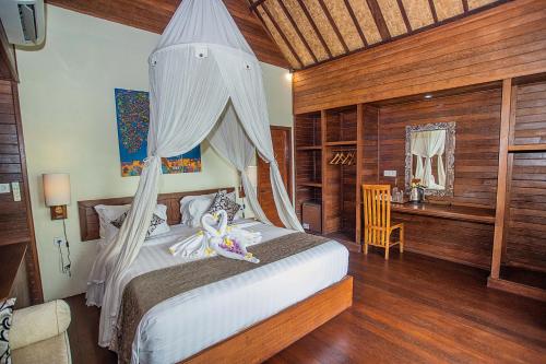 a bedroom with a bed with a mosquito net at D'Muncuk Huts Lembongan in Nusa Lembongan