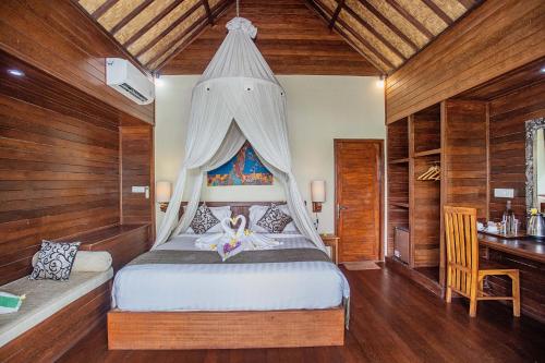 D'Muncuk Huts Lembongan في نوسا ليمبونغان: غرفة نوم بسرير مع مظلة