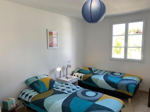 deux lits côte à côte dans une pièce dans l'établissement Maison 3 chambres au calme, 3* - Proche plage et commerces, WiFi, terrasse, jardin, TV box, garage - FR-1-323-525, à Saint-Jean-de-Monts