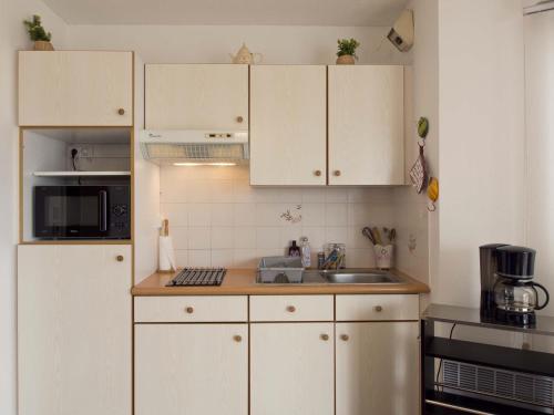 une cuisine avec des armoires blanches et un évier dans l'établissement Studio lumineux à 250m de la plage - Quartier Arago, proche commerces - FR-1-92-938, à Les Sables-dʼOlonne