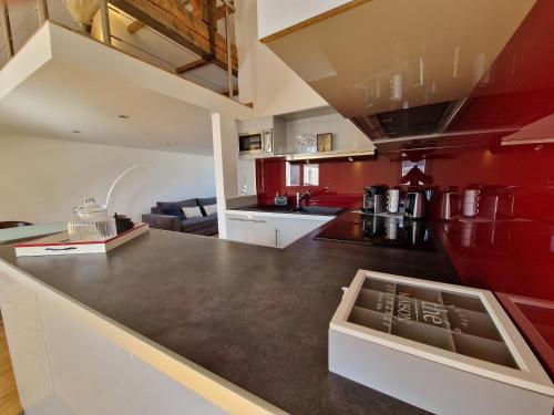 une cuisine avec des murs rouges et un comptoir noir dans l'établissement Loft 4 pers centre Châtelaillon-Plage, à deux pas de la mer et du Casino, Wi-Fi inclus - FR-1-706-26, à Châtelaillon-Plage