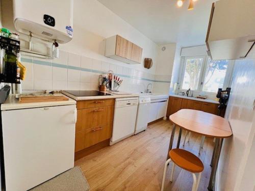 - une cuisine avec des appareils blancs et une table en bois dans l'établissement Appartement lumineux refait à neuf, centre-ville, proche plage, balcon sud, parking, WIFI - FR-1-478-271, à Quiberon