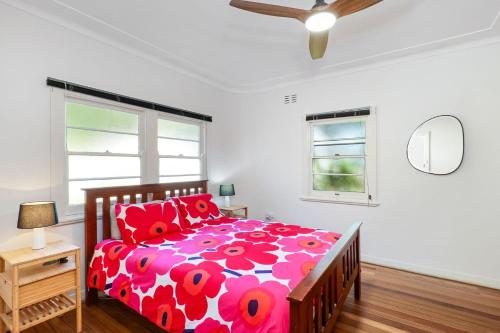 a bedroom with a bed with a red and white comforter at Place au Soleil in Coffs Harbour