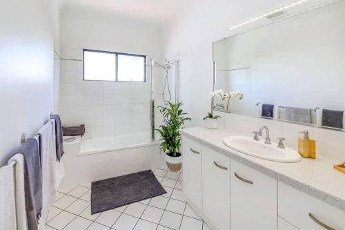 a white bathroom with a sink and a mirror at Alex Heads Beach Haven in Alexandra Headland