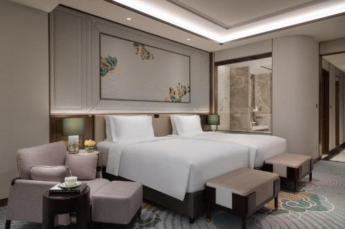 a bedroom with a large white bed and chairs at Sofitel Xiong An in Baoding