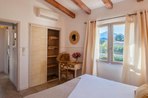 a bedroom with a bed and a desk and a window at Beautiful Apartment Hortensia with large terrace for 46 people in Calvi