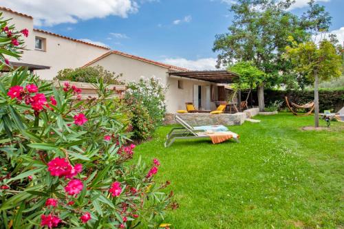 une cour avec des fleurs roses et une maison dans l'établissement Very warm villa "Acacia" with beautiful garden - 46 people, à Calvi