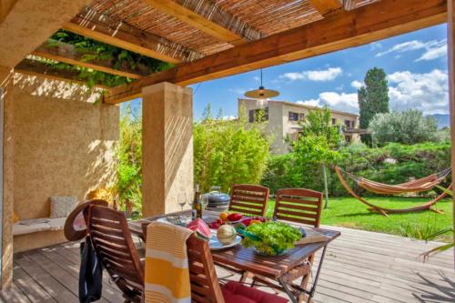 a patio with a table and chairs and a hammock at Maisonnette une chambre "Yucca" 2 à 4 personnes in Calvi