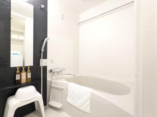 a white bathroom with a tub and a sink at ESLEAD HOTEL Osaka Ebisu in Osaka