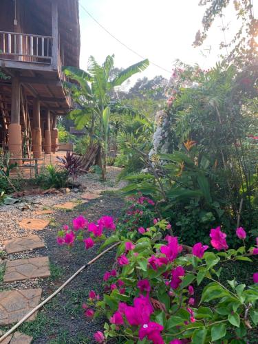 a garden with pink flowers in front of a house at Chà Là retreat BMT in Buon Ma Thuot