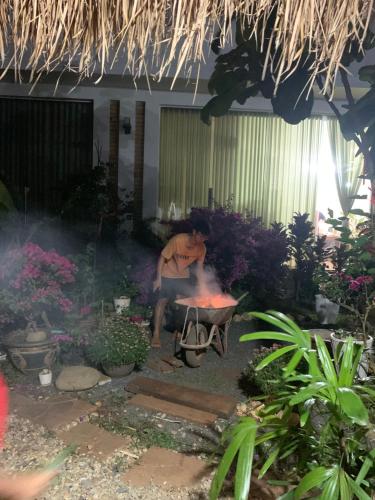 a man sitting in front of a fire in a garden at Chà Là retreat BMT in Buon Ma Thuot