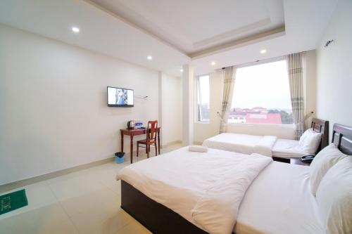 a hotel room with two beds and a tv at Thành Nghiêm Hotel Ninh Hòa in Ninh Hòa
