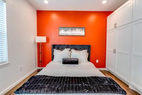 Cama en habitación con pared de color naranja en Velouté Valor - 1BD Near Med Center & Museum District, en Houston