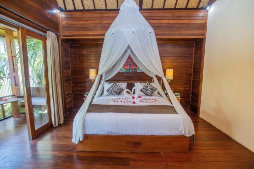 a bedroom with a bed with a canopy at D'Muncuk Huts Lembongan in Nusa Lembongan