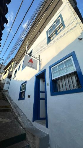 um edifício branco com uma porta azul e uma placa em Hostel e Pousada Mineira em Ouro Preto