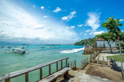 a boat in the water next to a beach at D'Muncuk Huts Lembongan in Nusa Lembongan