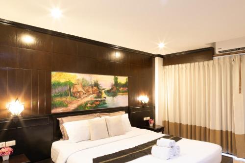 a bedroom with two beds and a painting on the wall at Best Venue Hotel in Patong Beach