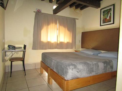 1 dormitorio con cama, mesa y ventana en Ruma San Luis Hotel Boutique, en San Luis Potosí