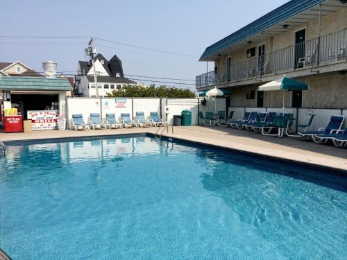 a swimming pool at a hotel with chairs and a building at Sand Pebble Motor Lodge in Point Pleasant Beach