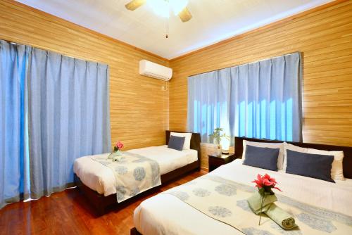 a bedroom with two beds and blue curtains at 広い庭付きBBQ可,残波ビーチまで車で5分,最大人数11名 Ns garden in Jima