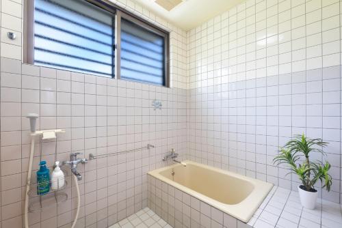 a white tiled bathroom with a bath tub at 広い庭付きBBQ可,残波ビーチまで車で5分,最大人数11名 Ns garden in Jima