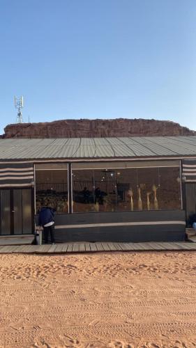 a man sitting in front of a building with animals in the windows at Rum rose luxury camp in Wadi Rum