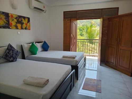 a room with two beds and a door to a balcony at Sun Set Forest Villa in Kandy