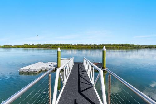 a dock with a boat on the water at Jasmine cove - Exclusive Waterfront Estate in Yamba
