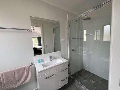 a white bathroom with a sink and a shower at Denman Van Village in Denman