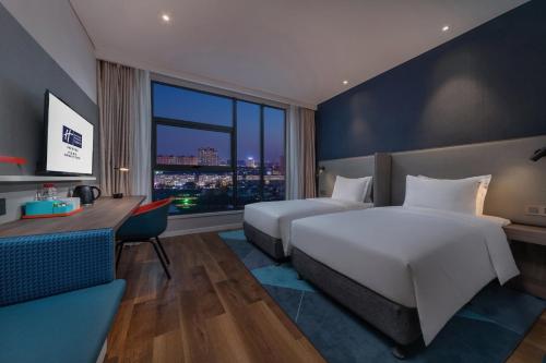 una camera d'albergo con due letti, una scrivania e una finestra di Holiday Inn Express Kaifeng City Center, an IHG Hotel a Kaifeng