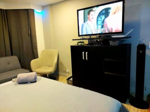 a hotel room with a bed and a flat screen tv at Executive Suites Minutes From the Airport in Bogotá