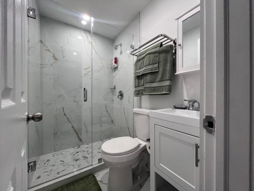 y baño blanco con aseo y ducha. en Modern apartment near Wynwood! en Miami