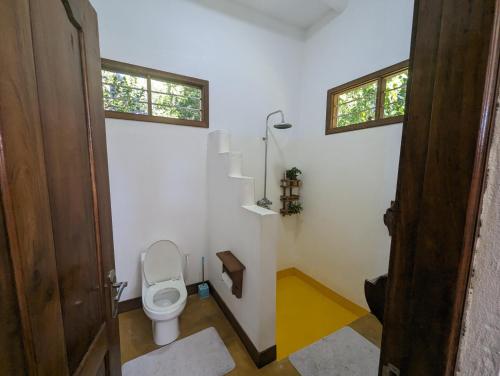 ein Badezimmer mit WC und zwei Fenstern in der Unterkunft Kivulini Lodge in Utende