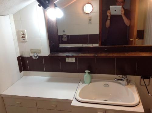 a woman taking a picture of a bathroom sink at Condominio Colmet in La Thuile