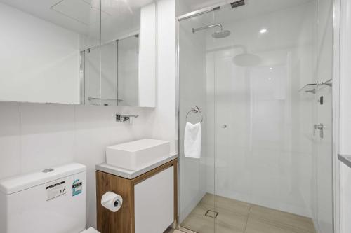 a white bathroom with a sink and a shower at Chic 1-Bed with Parking, Rooftop Pool and Gym in Brisbane