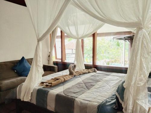 a bedroom with a canopy bed with mosquito nets at Javanese Joglo House by Malathi Ubud in Ubud