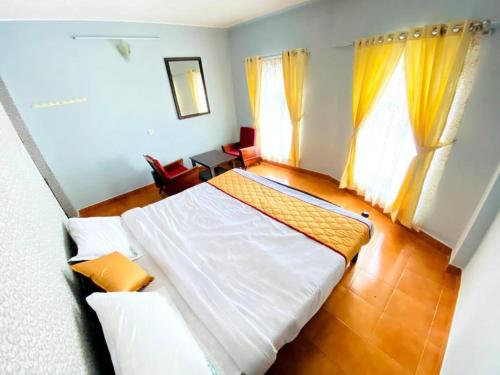 a bedroom with a large white bed with yellow curtains at BOB Leisure in Ooty