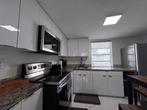 a kitchen with white cabinets and black appliances at Charming two bedroom apartment. in Miami