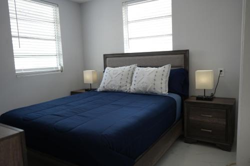 a bedroom with a blue bed with two night stands and two windows at Charming two bedroom apartment. in Miami