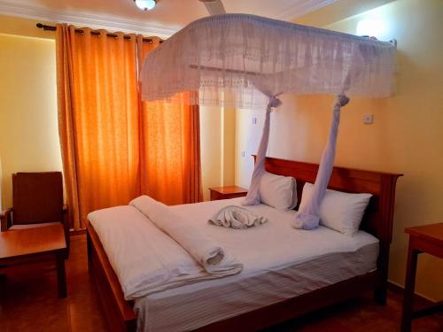 a bedroom with a canopy bed with white sheets at IZAK HOTEL in Dar es Salaam