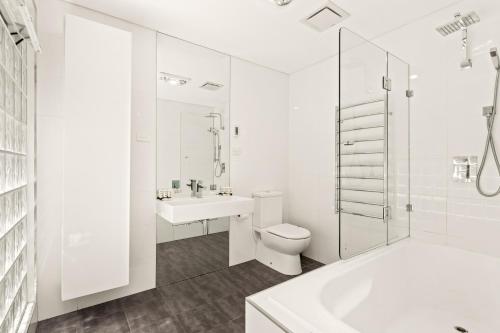 een witte badkamer met een toilet en een wastafel bij Chic 3-Bed House with a Cosy Courtyard in Sydney