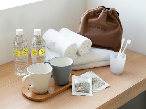 a table with cups and a purse and towels at Kaname Inn Tatemachi in Kanazawa