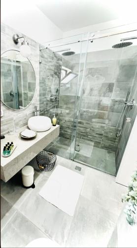 een badkamer met een douche, een wastafel en een spiegel bij בלקוני לחוף דור in Dor
