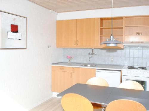 una cocina con armarios de madera, mesa y sillas en 4 person holiday home in Allinge en Allinge