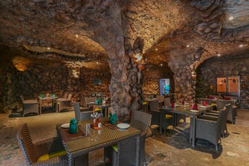 un restaurante con mesas y sillas en una pared de piedra en Summit Green Lake Tea Resort & Spa, en Kāziranga