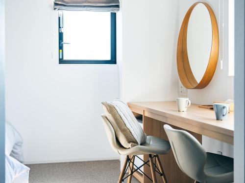 a bedroom with a mirror and a desk and chairs at Kaname Inn Tatemachi in Kanazawa