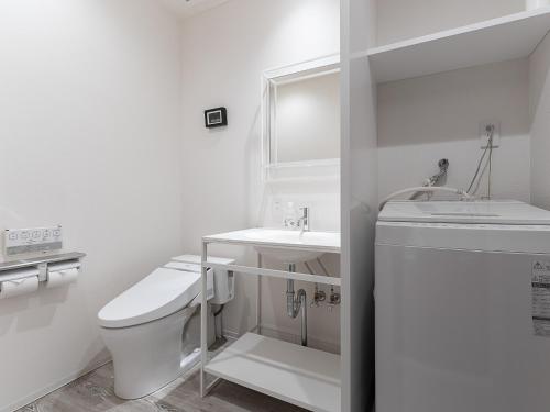 a white bathroom with a toilet and a sink at Kaname Inn Tatemachi in Kanazawa