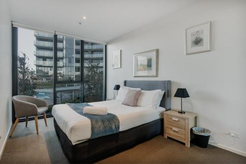 1 dormitorio con 1 cama, 1 silla y 1 ventana en Central Located 2-Bed with Pool, Gym & Parking, en Canberra